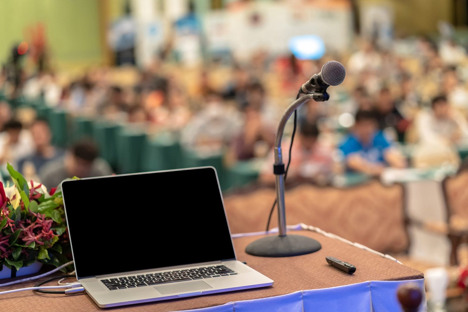 Microphone and tecgnology laptopn on the table over the Abstract blurred photo of conference hall or seminar room with audience background, education and learning concept